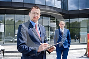 Business people signing contract near skyscraper outdoors