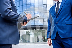 Business people signing contract near skyscraper outdoors