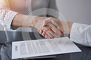 Business people signing contract papers while sitting at the glass table in office, closeup. Partners or lawyers working