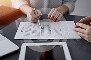 Business people signing contract papers while sitting at the glass table in office, closeup. Partners or lawyers working