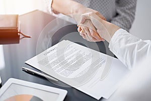 Business people signing contract papers while sitting at the glass table in office, closeup. Partners or lawyers working