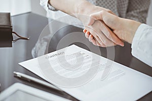 Business people signing contract papers while sitting at the glass table in office, closeup. Partners or lawyers working