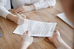 Business people signing contract papers while sitting at the wooden table in office, closeup. Partners or lawyers