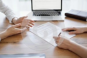 Business people signing contract papers while sitting at the wooden table in office, closeup. Partners or lawyers