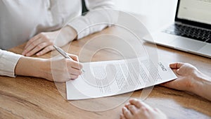 Business people signing contract papers while sitting at the wooden table in office, closeup. Partners or lawyers