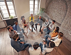 Business people sitting at circle in board room and discussing