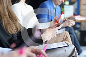 Business people sitting at conference and holding documents and mobile phones in hands closeup