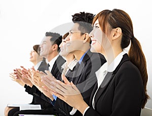 Business people sitting in a row and applauding