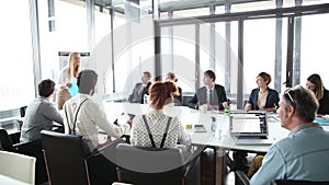 Business people sitting at table while female colleague giving presentation