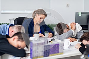 Business people sleeping in the office, while some still keep working