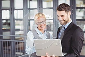 Business people smiling while looking at laptop