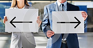 Business people standing while holding white Left and Right arrow placard in arrival area at airport