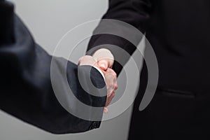 Business people in suit shaking hands on grey studio wall background. Success in business concept