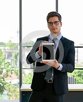 Business people in suit and tie  holding blank screen tablet computer with both hand. Morning work atmosphere in a modern office