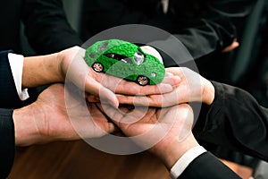 Business people synergy holding EV car model. Quaint