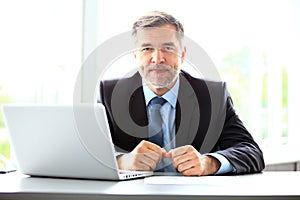 Business, people and technology concept - happy smiling businessman with laptop computer office