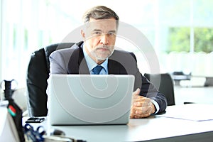 Business, people and technology concept - happy smiling businessman with laptop computer office