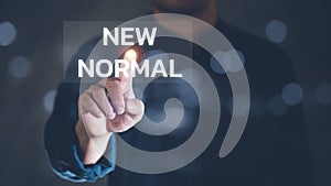 Business people use their fingers to touch the word `New normal`. Business concept for Make a big dramatic change Replace the ex