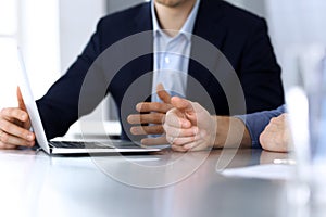 Business people using laptop computer while working together at the desk in modern office. Unknown businessman or male