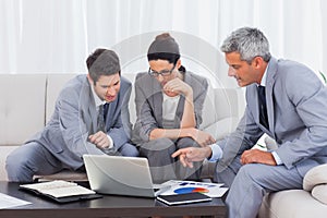 Business people using laptop and working together on sofa