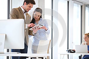 Business people using tablet computer with female colleague in background at office photo