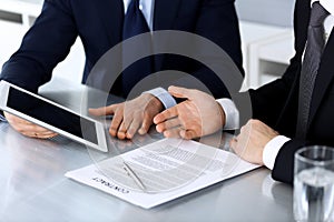 Business people using tablet computer while working together at the desk in modern office. Unknown businessman or male