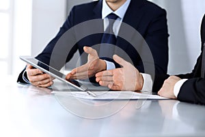 Business people using tablet computer while working together at the desk in modern office. Unknown businessman or male