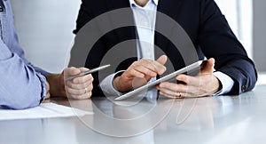Business people using tablet computer while working together at the desk in modern office. Unknown businessman or male