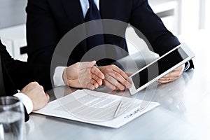 Business people using tablet computer while working together in modern office. Unknown businessman with colleague at