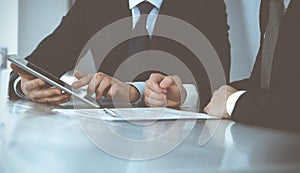 Business people using tablet computer while working together in modern office. Unknown businessman with colleague at