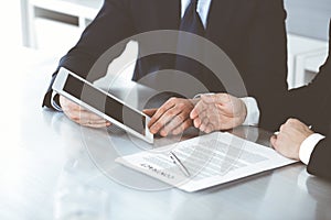 Business people using tablet computer while working together in modern office. Unknown businessman with colleague at