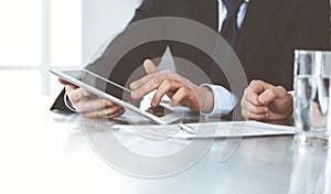 Business people using tablet computer while working together in modern office. Unknown businessman with colleague at