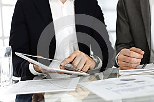 Business people using tablet computer while working together in modern office. Unknown businessman sitting at the desk