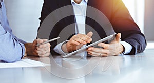Business people using tablet computer while working together in sunny modern office. Unknown businessman with colleague
