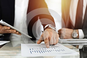 Business people using tablet computer while working together in sunny office. Unknown businessman sitting at the desk