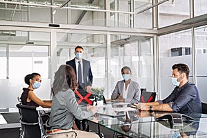 Business people wearing mask and keeping social distancing during meeting