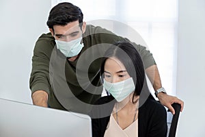 Business people wearing protective face mask discuss project look at computer screen in meeting room office, intern new employee,