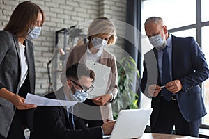 Business people wearing protective face masks while holding a presentation on a meeting during coronavirus epidemic
