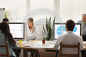 Business people working on computers sharing office desk in cowo