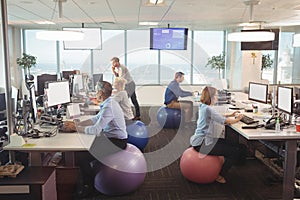 Business people working at desk while sitting on exercise balls