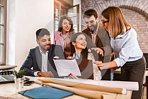 Business people working on new project and smiling. Man and women sitting together in modern office