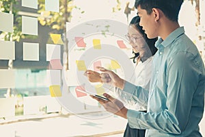Business people working planning discussing idea with sticky reminder note on glass wall