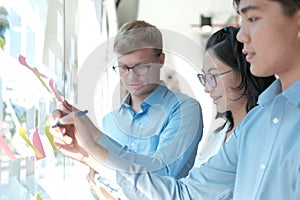 Business people working planning discussing idea with sticky reminder note on glass wall