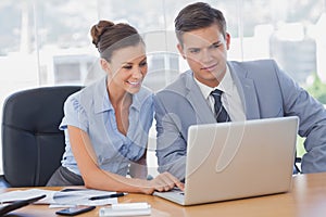 Business people working together on laptop and smiling