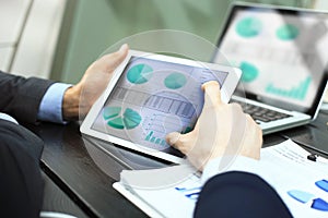 Business person analyzing financial statistics displayed on the tablet screen.