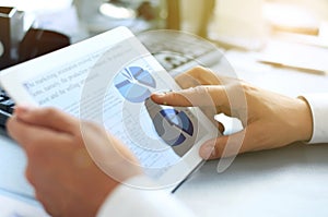 Business person analyzing financial statistics displayed on the tablet screen.