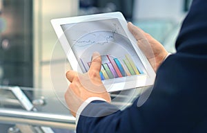 Business person analyzing financial statistics displayed on the tablet screen.