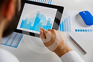 Business person analyzing financial statistics displayed on the tablet screen