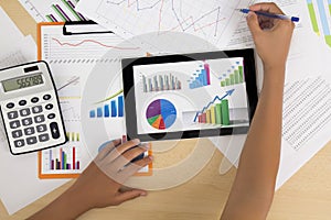 Business person analyzing financial statistics displayed on the tablet screen with a pen