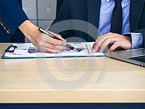 Business person checking report chart on desk in office